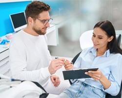 Dental patient holding clipboard, filling out paperwork
		  