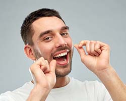 man flossing to prevent dental emergencies in Enfield