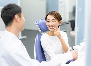 Patient smiling while pointing at her tooth