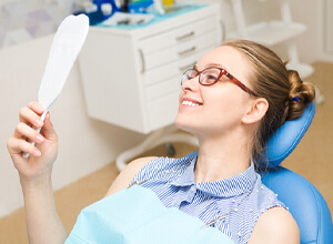 Woman admiring smile after 4 step dental implant process