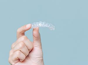 Hand holding an Invisalign® aligner in Enfield