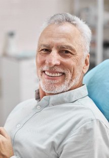man smiling while holding dental mirror 