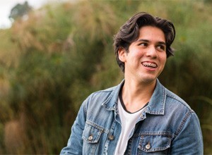 Smiling young man standing outside, wearing traditional braces