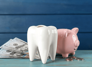 Piggybank, tooth model, and money arranged on tabletop