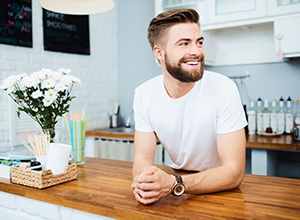 man smiling and leaning against counter