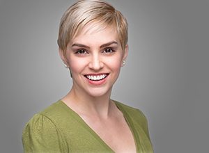 Smiling woman in green shirt, happy she could afford veneers