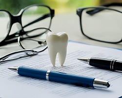 Tooth model and pens on top of insurance document