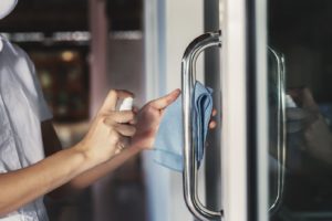 dental team member disinfecting practice door for patient safety