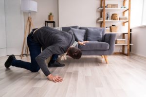 Man searching under sofa for lost Invisalign aligner