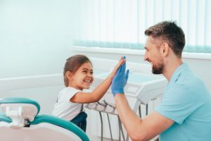 Girl high-fiving dentist after receiving dental sealants in Enfield