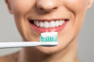 Woman brushing teeth to extend lifespan of veneers in Enfield