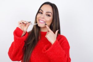 Happy woman holding aligner, fixing TMJ with Invisalign