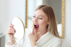 Young woman inspecting her teeth in mirror 