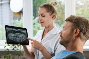 Dental team member pointing at wisdom tooth on patient’s X-ray